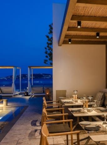 Luxurious white-washed Greek hotel overlooking azure Aegean waters, with elegant infinity pool and minimalist Cycladic architectural design in Mykonos