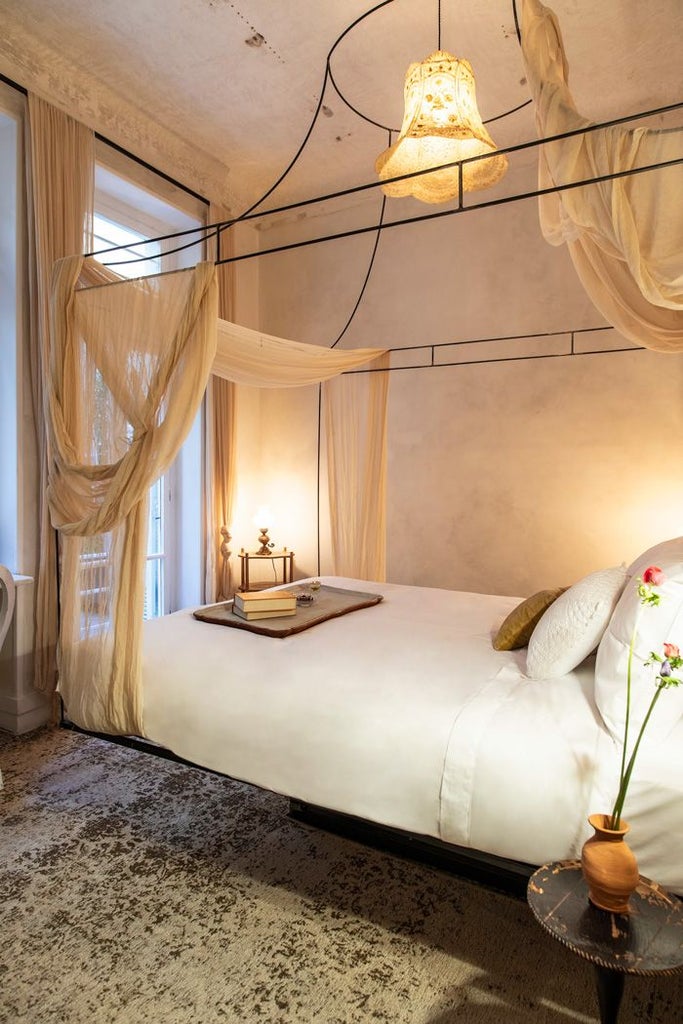 Minimalist luxury hotel room with soft dusty rose walls, elegant white bed linens, and warm ambient lighting in Athens boutique hotel