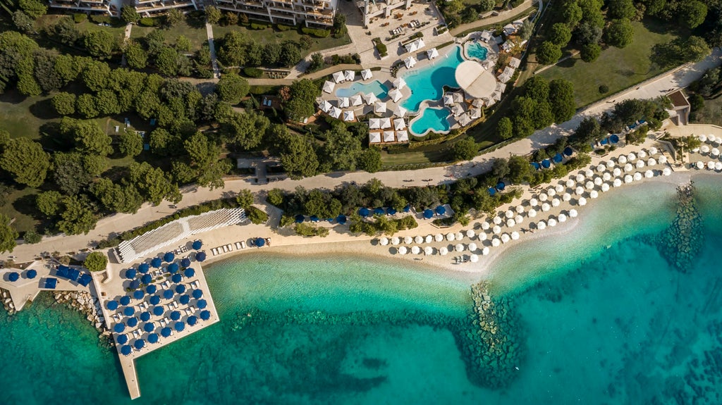 Elegant five-star Monte Mulini Hotel exterior with palm trees, modern glass facade, and ocean-view terrace overlooking Adriatic Sea in Croatia