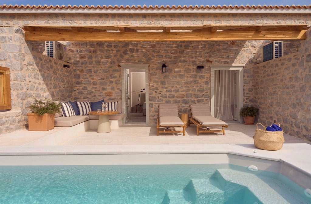 Elegant beachfront suite featuring floor-to-ceiling windows, private infinity pool overlooking Mediterranean Sea, and modern white decor