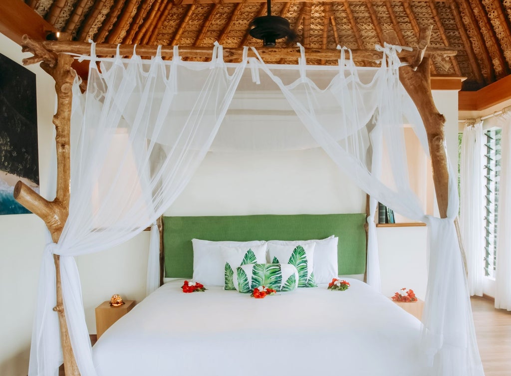 Luxurious Vonu Point Villa bedroom with sweeping ocean views, wooden floors, plush white bedding, and elegant tropical decor in Fiji's serene landscape