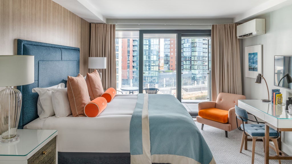 Elegant double room at Harbour Hotel Southampton with plush bedding, modern decor, and a Juliet balcony overlooking scenic urban landscape, showcasing contemporary UK hospitality design