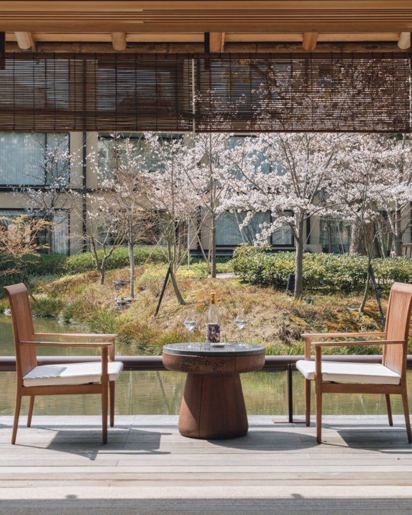 Traditional Japanese garden with stone pathways and maple trees surrounding a serene pond at Four Seasons Kyoto's inner courtyard