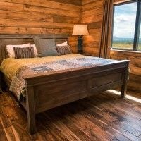 Rustic lodge room with wooden furnishings, plush bedding, and large windows overlooking scenic mountain landscape at Ranch accommodation near natural park