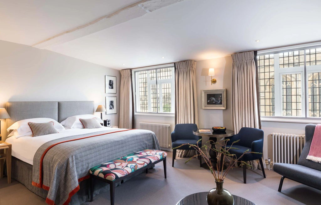 Elegant deluxe hotel room with classic British architecture, antique wooden furnishings, and luxurious soft lighting in a historic bank building interior