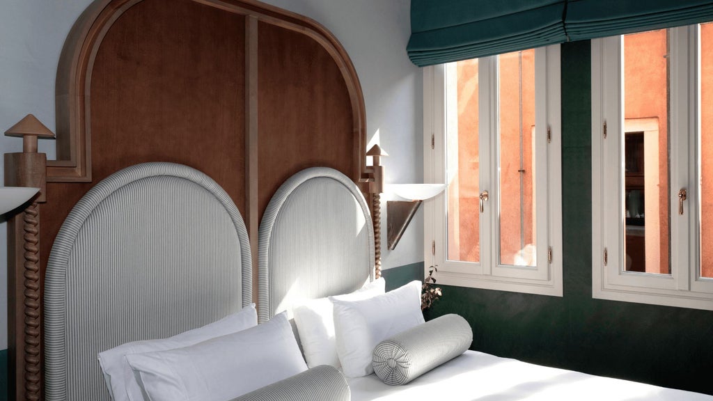 Elegant single room with soft beige walls, luxurious white linens, minimalist wooden furniture, and warm ambient lighting in an Italian boutique hotel.