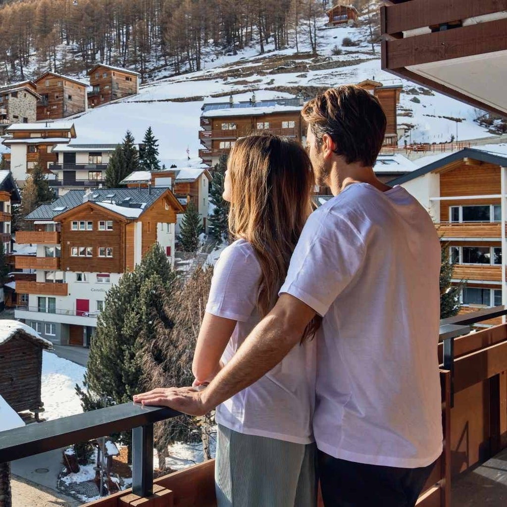 Luxurious alpine hotel nestled in Swiss mountains, featuring modern chalet-style architecture with panoramic snow-capped mountain views and elegant wooden exterior