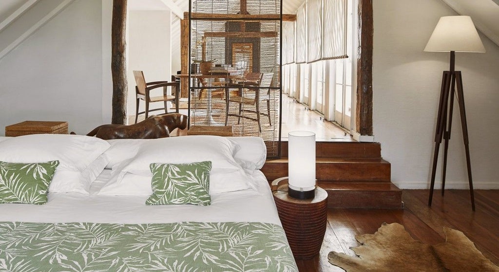 Elegantly styled deluxe hotel room with contemporary Brazilian decor, featuring a private balcony overlooking scenic scenset landscape in Rio de Janeiro