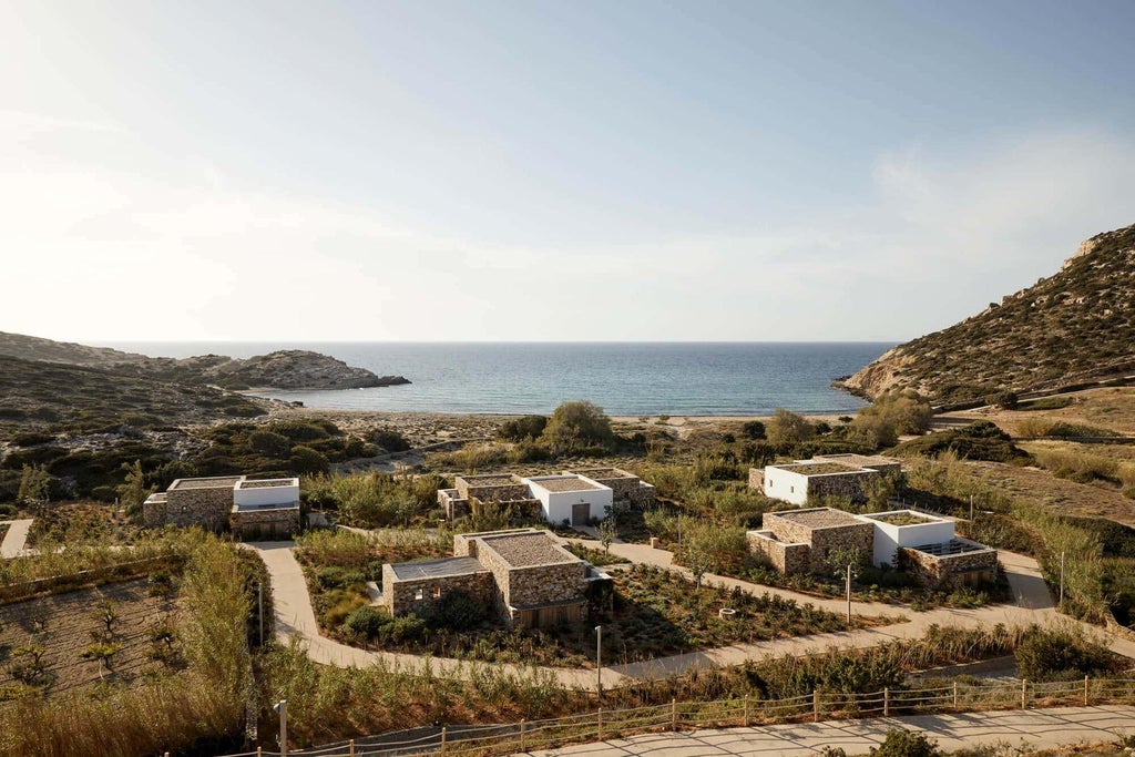 Minimalist beige luxury villa with private infinity pool overlooking the Aegean Sea, nestled into a rugged Greek hillside at sunset