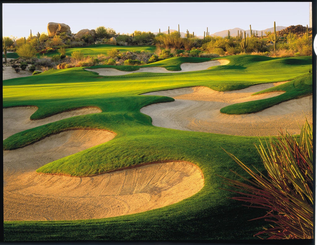 Elegant desert resort with adobe-style architecture nestled in Sonoran foothills, featuring cascading pools and mountain views at sunset