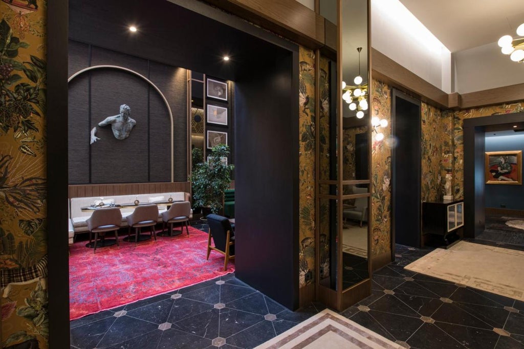 Elegant marble-clad lobby of Umiltà 36 hotel featuring crystal chandeliers, plush seating, and ornate gold-framed mirrors in Rome.