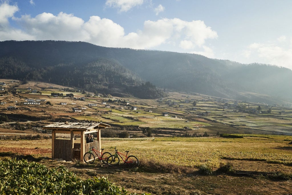 Bird's-eye view of luxurious wooden lodge perched on Himalayan hillside, featuring panoramic valley views and traditional Bhutanese architecture