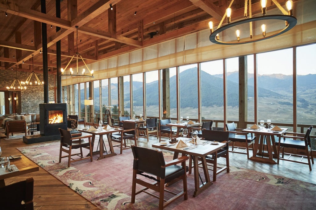 Traditional Bhutanese lodge perched on hillside overlooking misty Gangtey valley, featuring wooden architecture and floor-to-ceiling windows