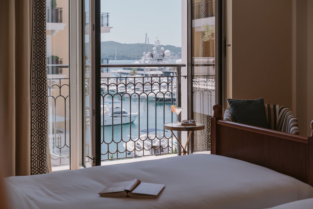 Elegant waterfront hotel with grand Mediterranean architecture, private marina, and mountain backdrop at sunset in Porto Montenegro