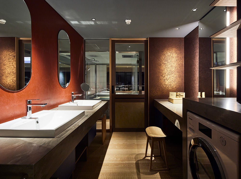 Traditional Japanese ryokan hotel with wooden facade, lanterns, and sliding doors, set against modern architecture in evening light