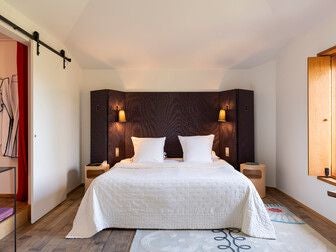 Luxurious spacious hotel room at the Manor Troisgros, featuring elegant French decor, large windows with soft natural light, and sophisticated minimalist design