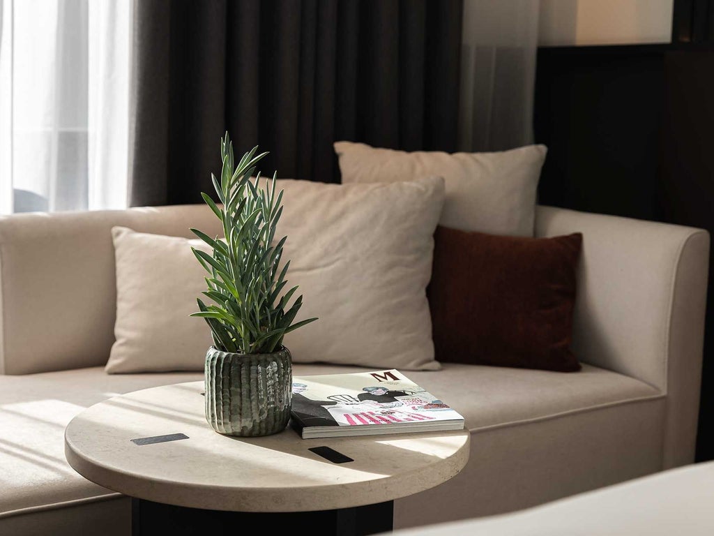 Luxurious hotel room with modern design, elegant gray furnishings, plush king bed, and expansive city view at Almanac X Alcron in Prague, Czech Republic