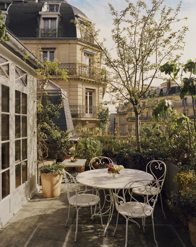 Elegant Parisian suite with plush ivory bedding, ornate gold-framed mirror, antique writing desk, and soft ambient lighting in historical Château Voltaire