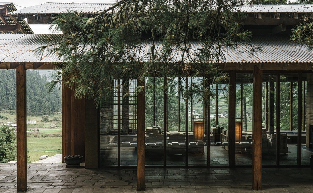 Luxurious mountain lodge with floor-to-ceiling windows overlooking Bhutanese valley, featuring traditional architecture and outdoor terrace