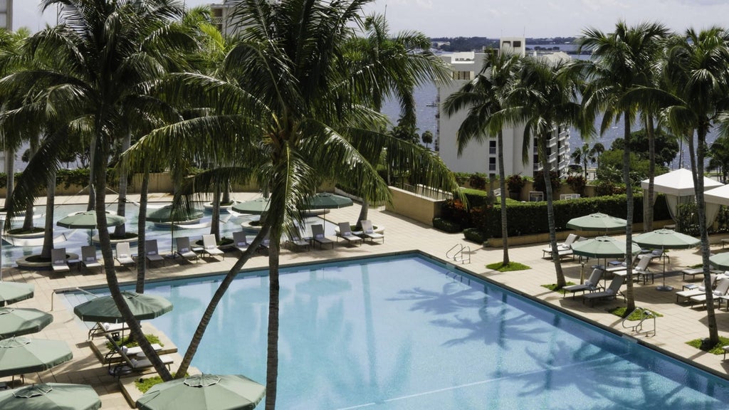 Luxurious glass-paneled Four Seasons hotel tower rising against a vibrant Miami skyline, showcasing modern architectural elegance and tropical urban landscape.