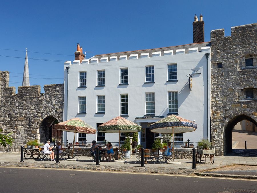 Historic stone hotel exterior with charming medieval architecture, rustic windows, and warm lighting nestled in a traditional British city wall setting at dusk