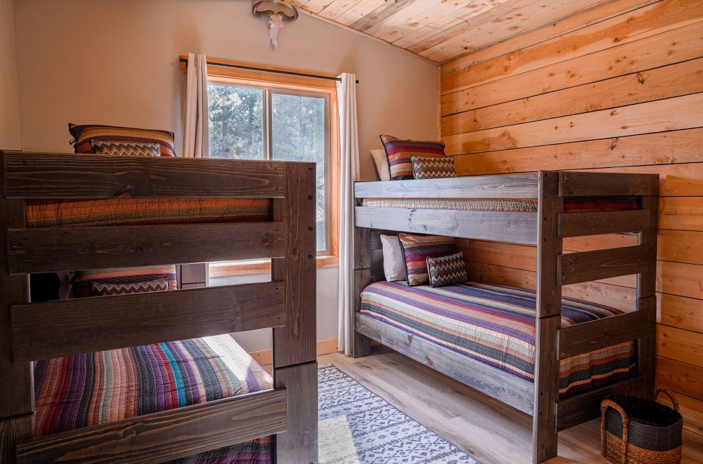 Rustic wooden lodge room with plush bedding, expansive mountain views, warm earth tones, and elegant Western-inspired decor at Scenset Mountain Ranch