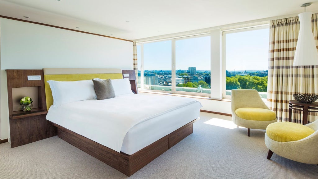 Luxurious COMO Suite with elegant contemporary design, plush white bed, minimal decor, and soft natural lighting in a high-end London hotel room.