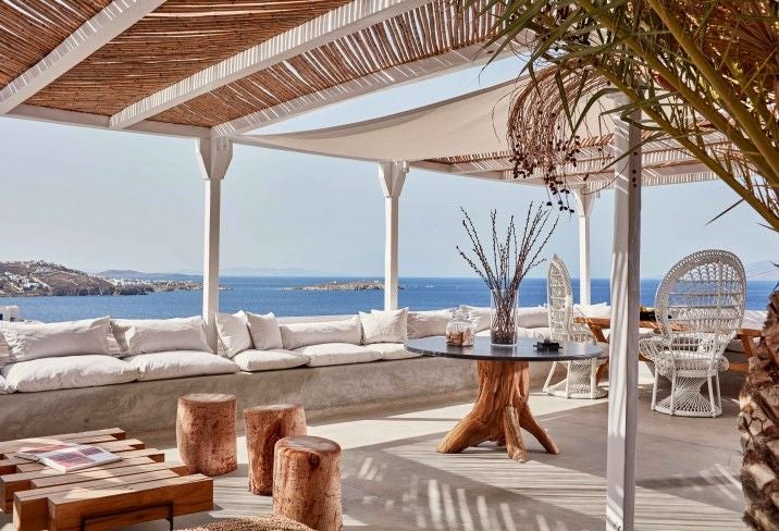 Whitewashed luxury villa with infinity pool overlooking Aegean Sea, featuring curved architecture and traditional Greek design at sunset