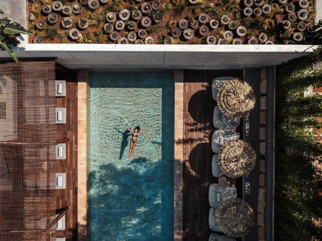 Luxurious white-washed Mediterranean hotel with minimalist design, infinity pool overlooking scenic Ibiza coastline at golden sunset hour