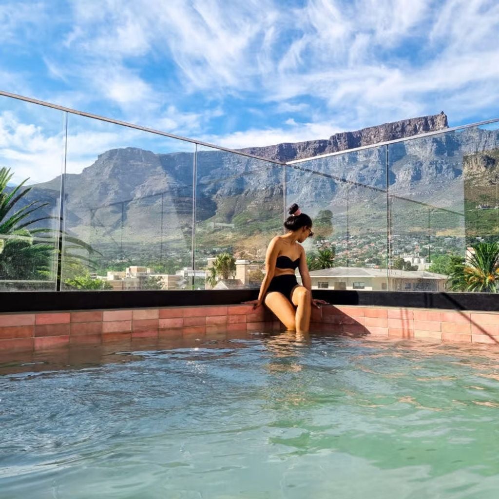 Modern luxury hotel exterior with glass balconies, sleek white facade and rooftop terrace overlooking Table Mountain in Cape Town