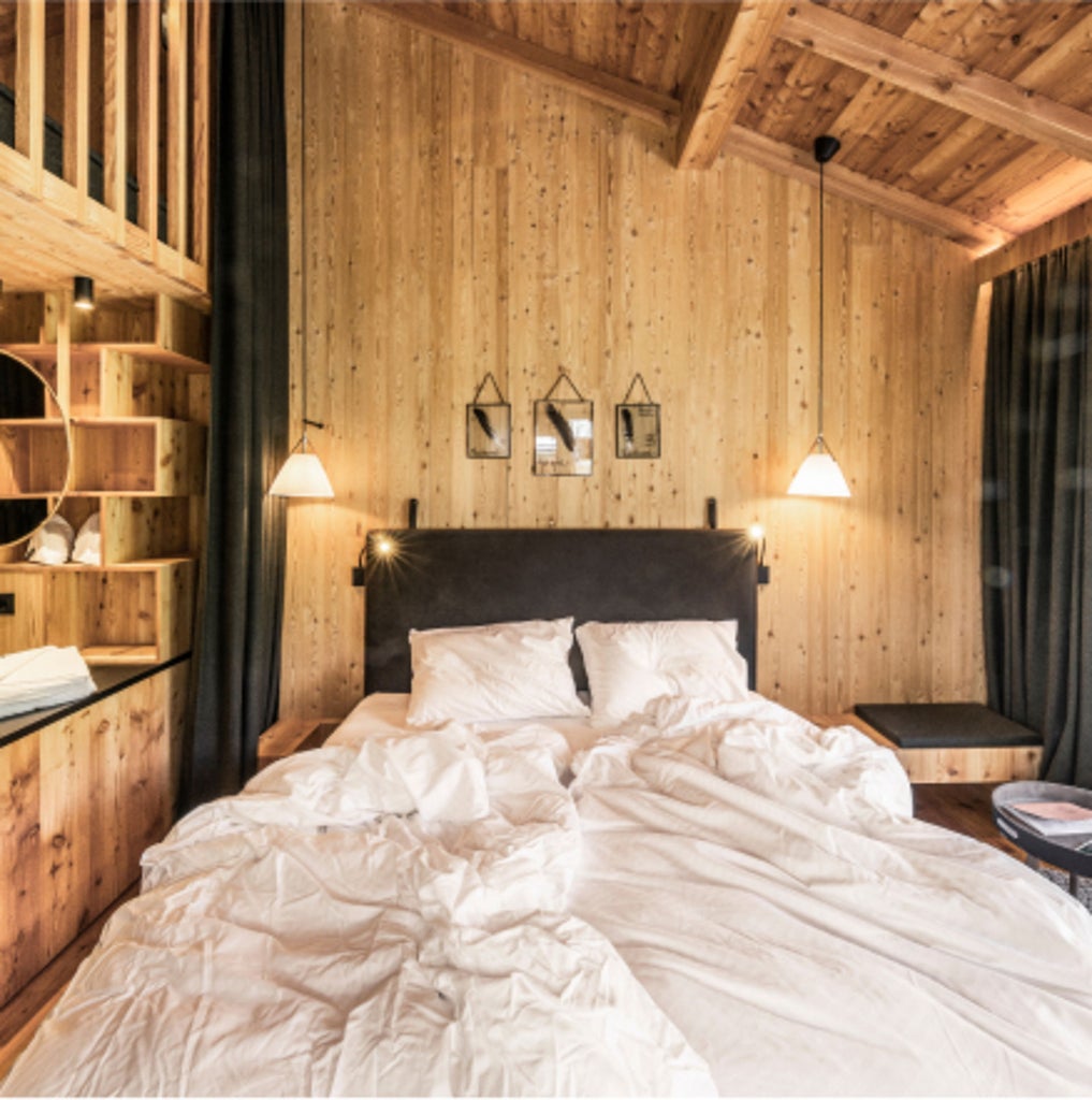 Traditional alpine lodge with modern glass facade nestled in snowy Dolomites mountains, featuring sleek Nordic-style cabins