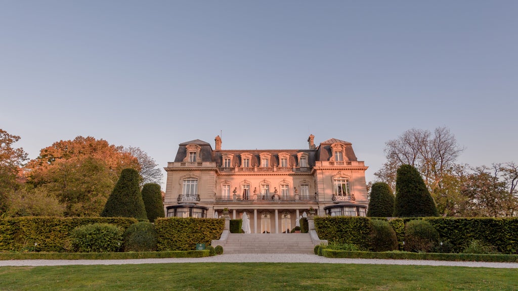 Elegant French château hotel with manicured gardens, ornate architecture, and cream-colored facade set against vibrant green lawns