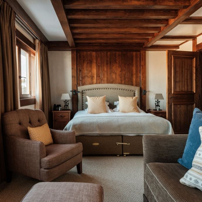 Luxurious alpine-style family suite at Portetta Hotel, featuring warm wooden accents, plush bedding, and panoramic mountain views in the French Alps