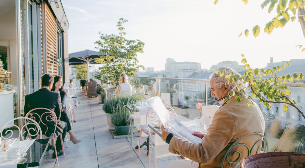 Luxurious rooftop terrace of Grand Ferdinand hotel in Vienna, Austria, overlooking historic cityscape with elegant white loungers and panoramic urban views