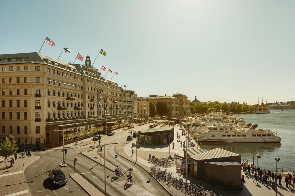 Historic Swedish luxury hotel with grand neoclassical facade, ornate balconies, illuminated golden signage, and waterfront location