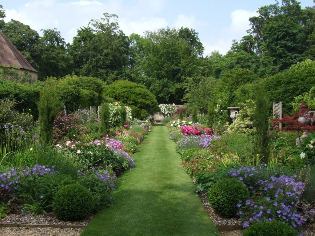 Elegant country house hotel with manicured gardens, grand Georgian architecture, and tree-lined driveway in lush English countryside landscape