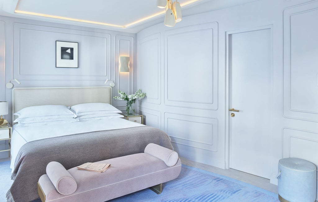 Elegant hotel room with contemporary design, plush king bed, floor-to-ceiling windows overlooking city, luxurious marble bathroom, and modern minimalist decor at One Aldwych