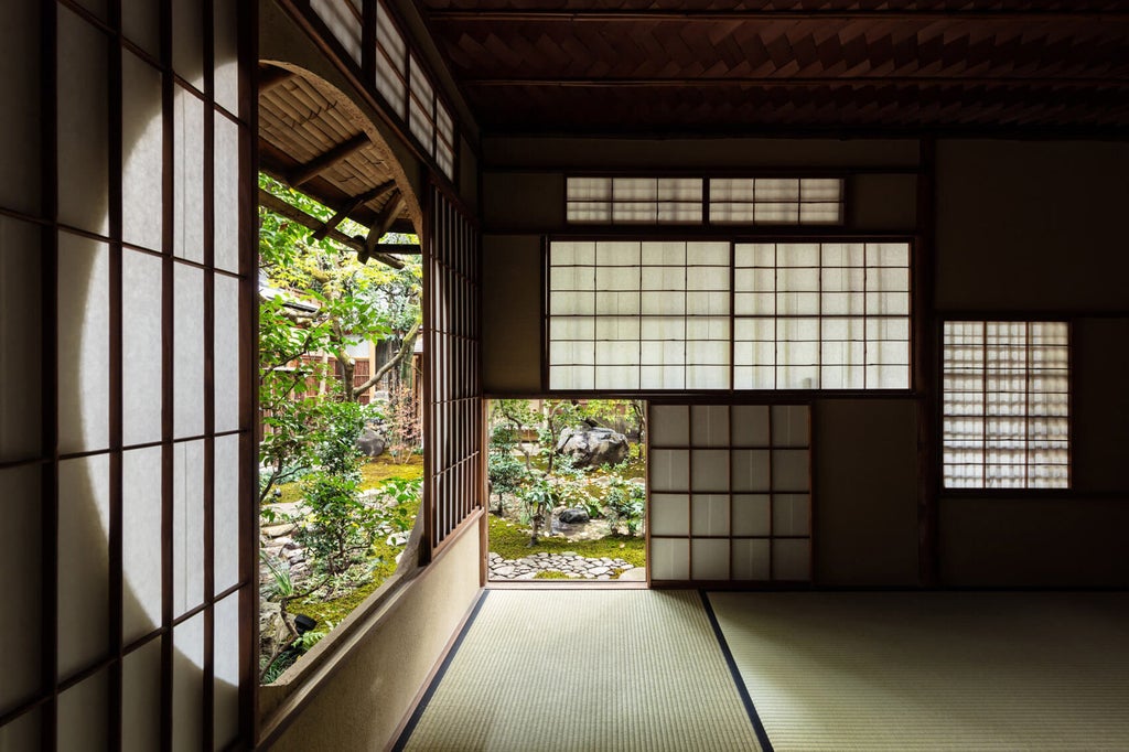 Traditional Japanese ryokan with modern design featuring a tranquil garden courtyard, wooden facade, and elegant stone pathway in Kyoto