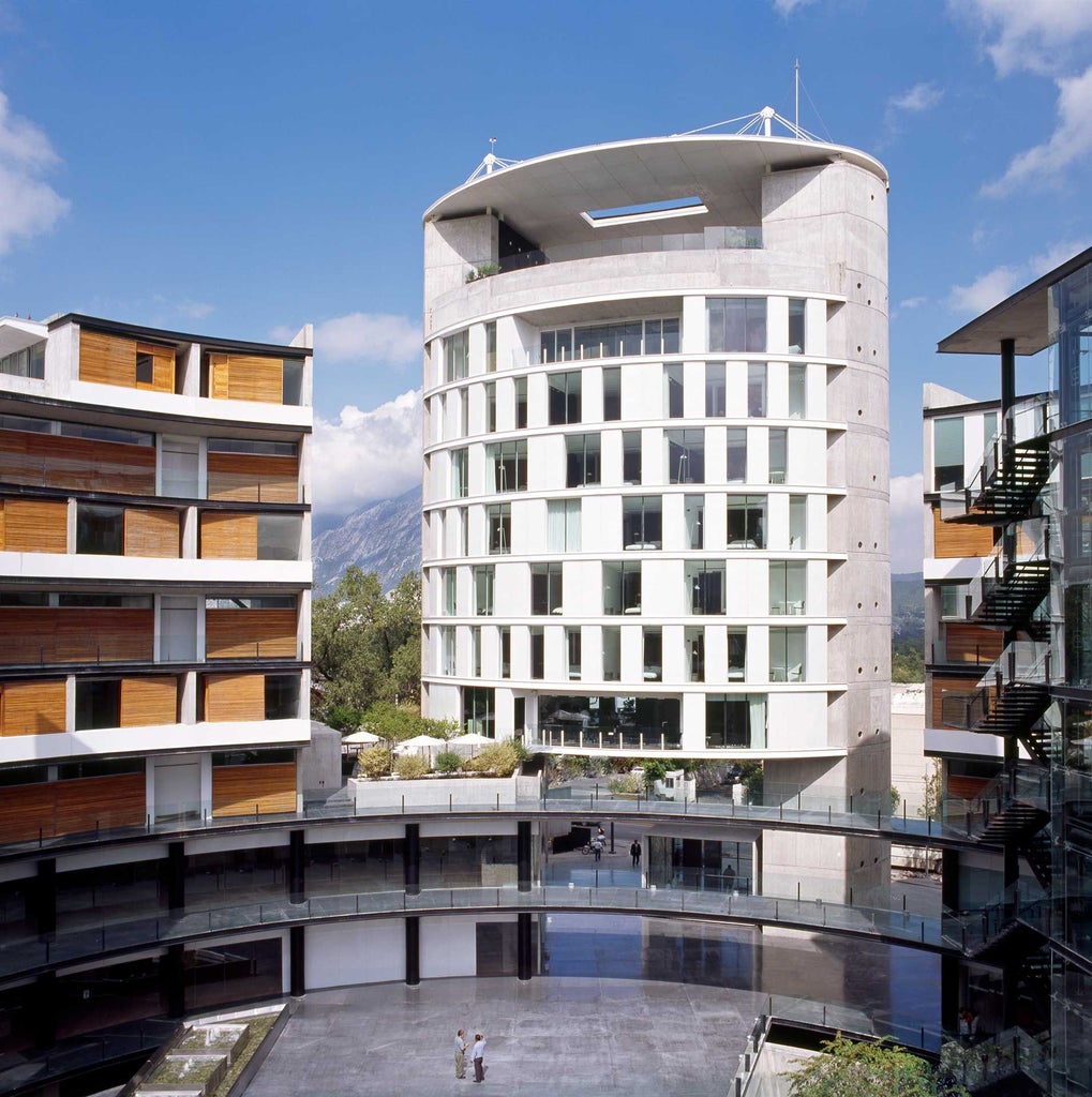 Modern glass-fronted hotel with sleek architectural design, minimalist white facade, reflecting sunset light in urban Monterrey skyline with contemporary geometric lines