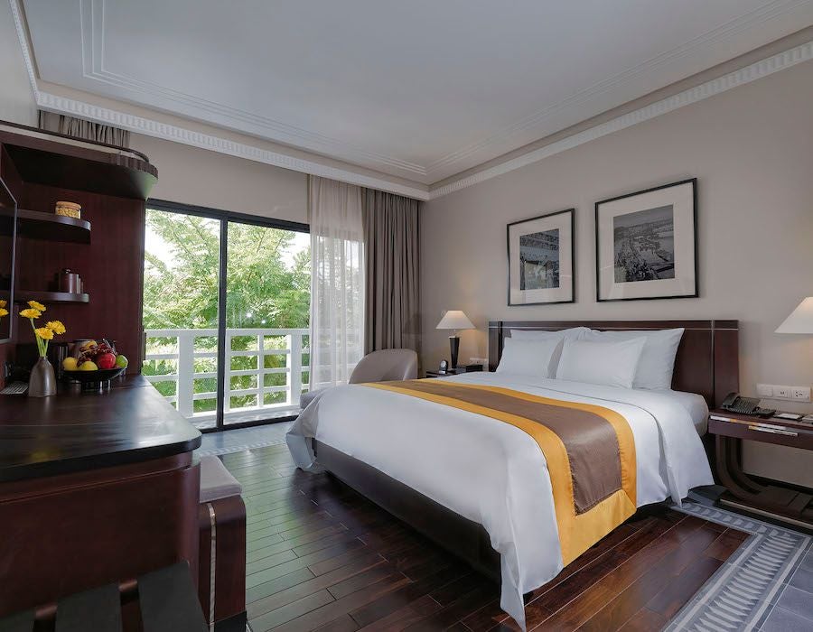 Elegant colonial-style superior hotel room at Azerai La Residence with refined decor, white walls, wooden furnishings, and soft natural lighting in Hue, Vietnam