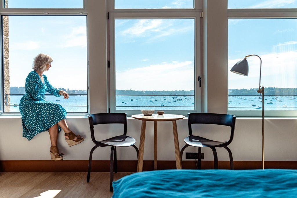 Luxurious seaside hotel with blue-gray facade overlooking rocky Brittany coastline, elegant balconies and classic French architectural charm at Scenset Hotel