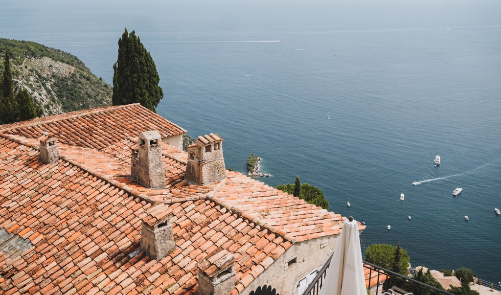 Aerial view of luxury yachts docked in turquoise Mediterranean waters along Nice's coastline, with historic French architecture lining the shore