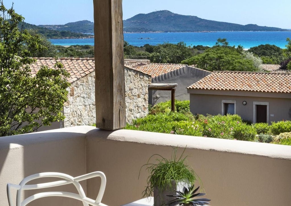 Modern Mediterranean-style luxury resort with white buildings, terracotta roofs, and palm trees overlooking pristine Sardinian coastline