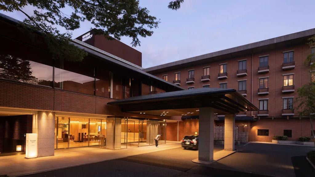 Modern high-rise Hyatt Regency hotel in Japan with glass facade, illuminated entrance and traditional Japanese garden elements at dusk