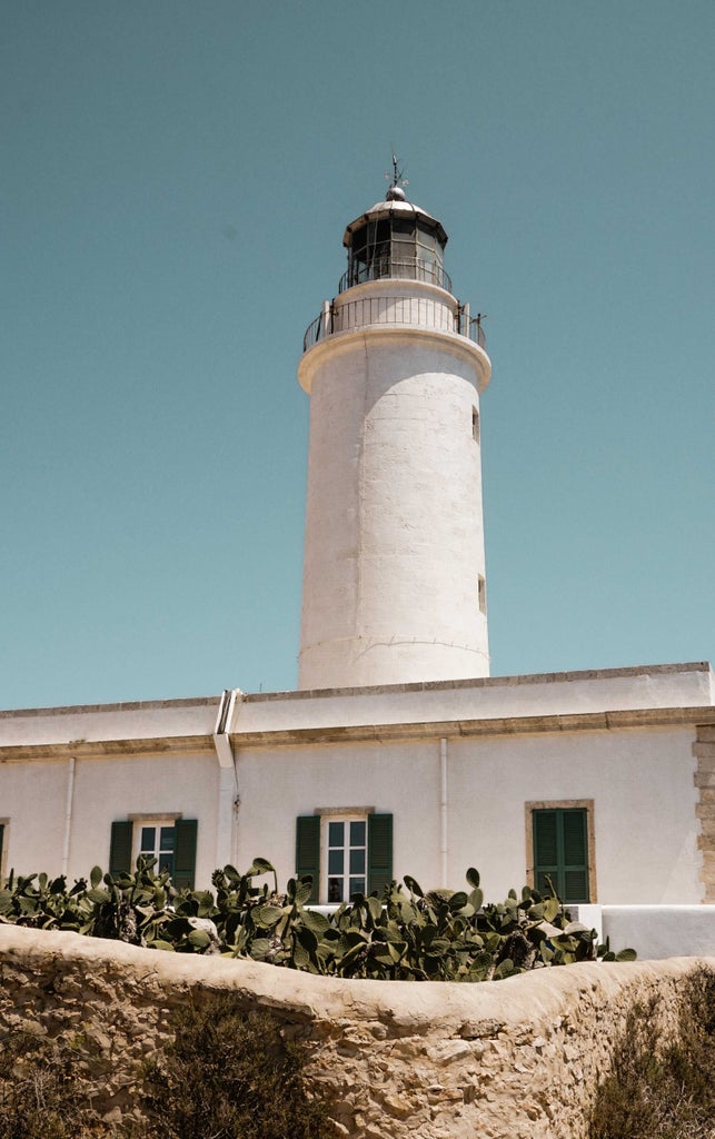 Bright turquoise waters meet white sandy beaches along Formentera's pristine coastline, with luxury yachts dotting the Mediterranean horizon