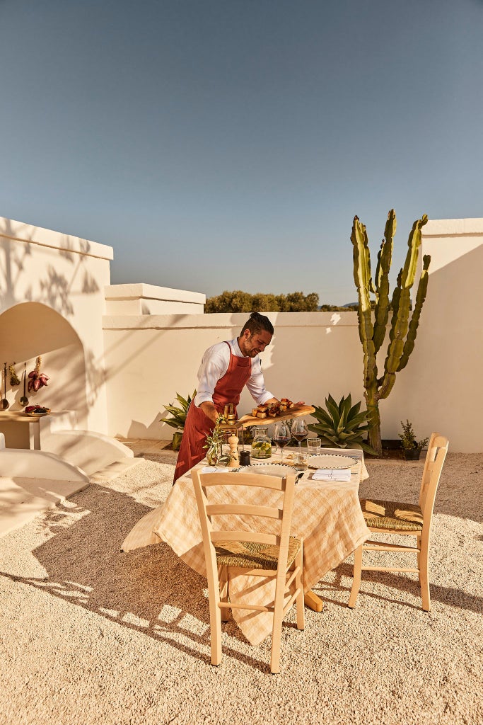 Rustic stone villa nestled in golden Italian countryside, surrounded by olive groves, with elegant whitewashed walls and terracotta roof under soft Mediterranean sunlight