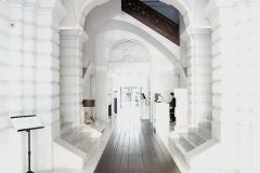 Elegant white-walled luxury hotel exterior with blue sky, featuring Mediterranean architectural details and lush tropical palm trees in Valencia, Spain