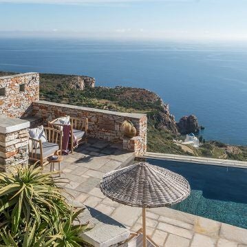 Luxurious whitewashed Cycladic hotel with minimalist design overlooking the azure Aegean Sea, featuring infinity pool and stunning sunset views in Greece