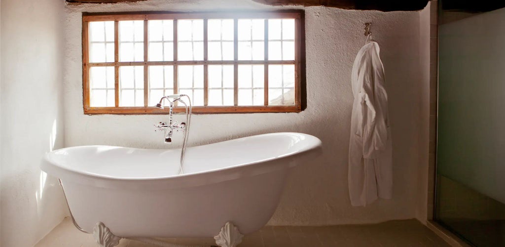 Elegant Spanish colonial suite with panoramic mountain views, ornate white linens, rustic wooden furniture, and warm natural light streaming through arched windows