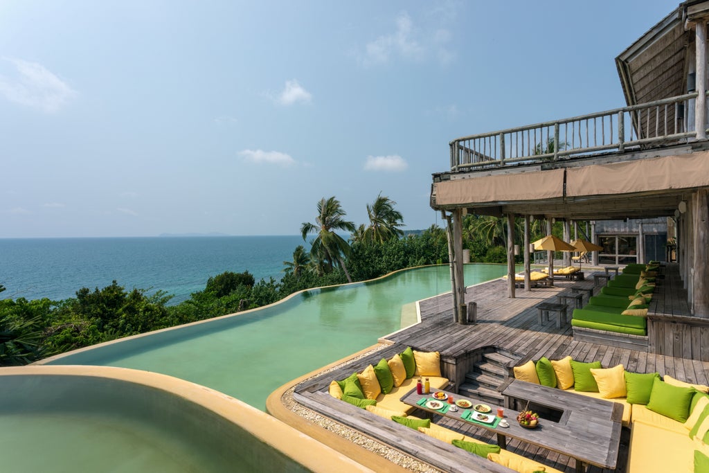 Luxurious overwater villa perched above turquoise waters in Koh Kood, featuring private infinity pool and teak wood deck with ocean views